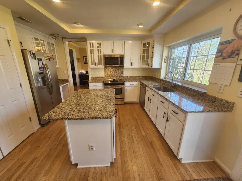 Bright kitchen featuring freshly painted white cabinets, light yellow walls, and granite countertops.