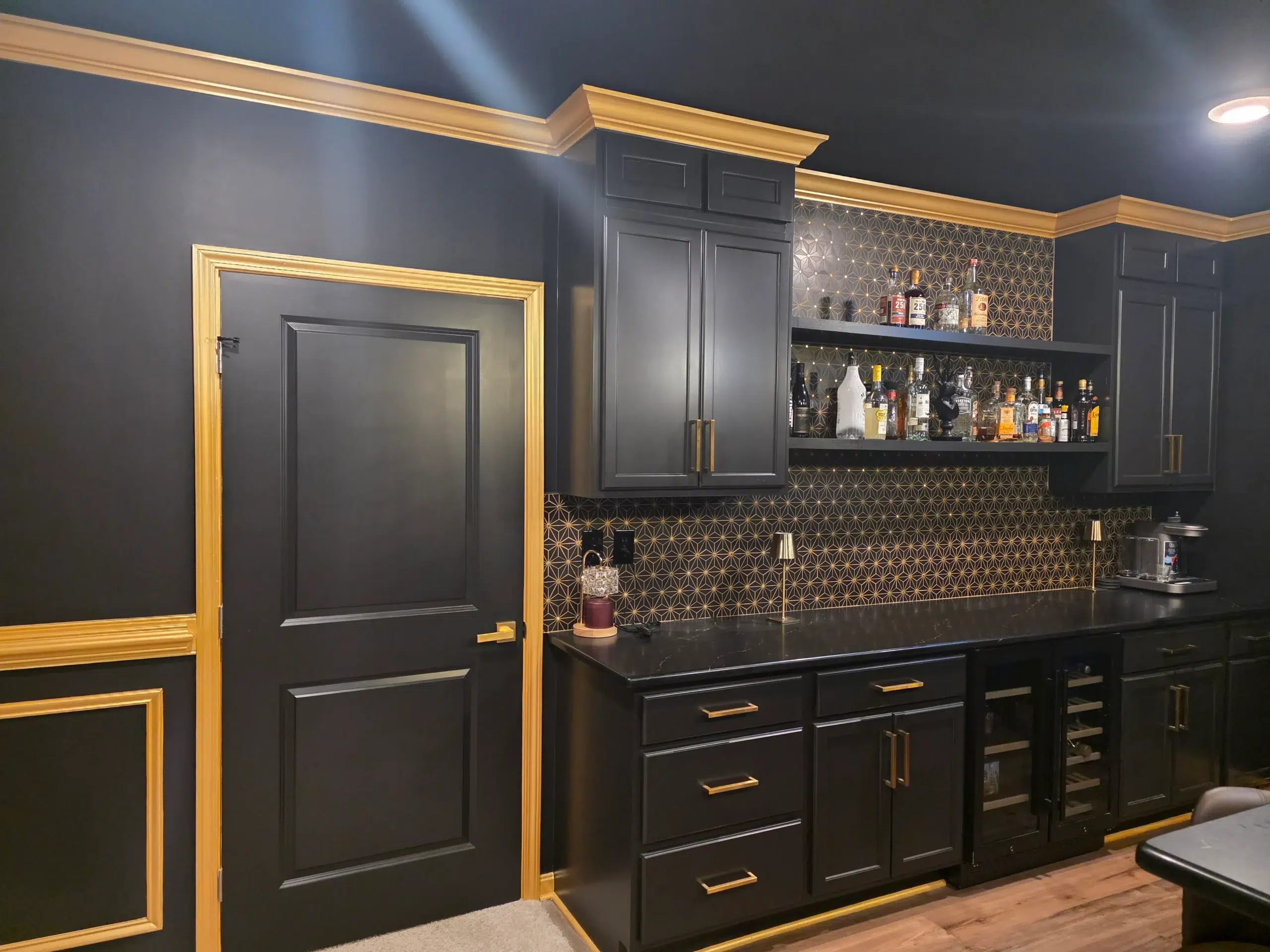 Luxurious Basement Bar Painting with Black Walls and Gold Trim A stylish home bar with black walls, black cabinets, and elegant gold trim accents.