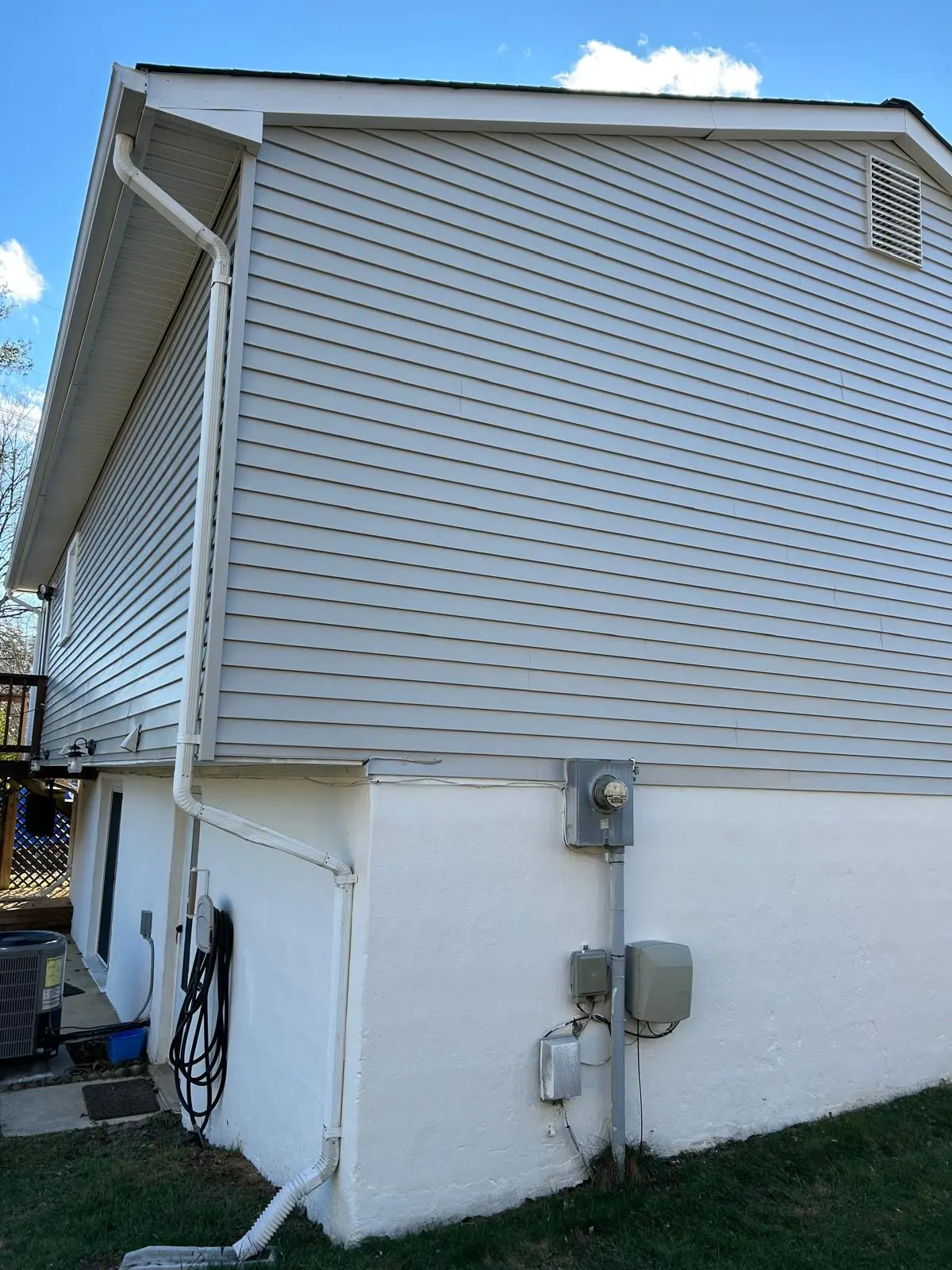 Residential Exterior Painting Services for Siding and Foundation The exterior of a house featuring light gray siding, white painted foundation, and white gutters.
